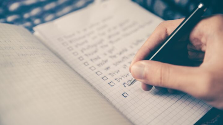 Jemand führt eine Checkliste in einem Heft.